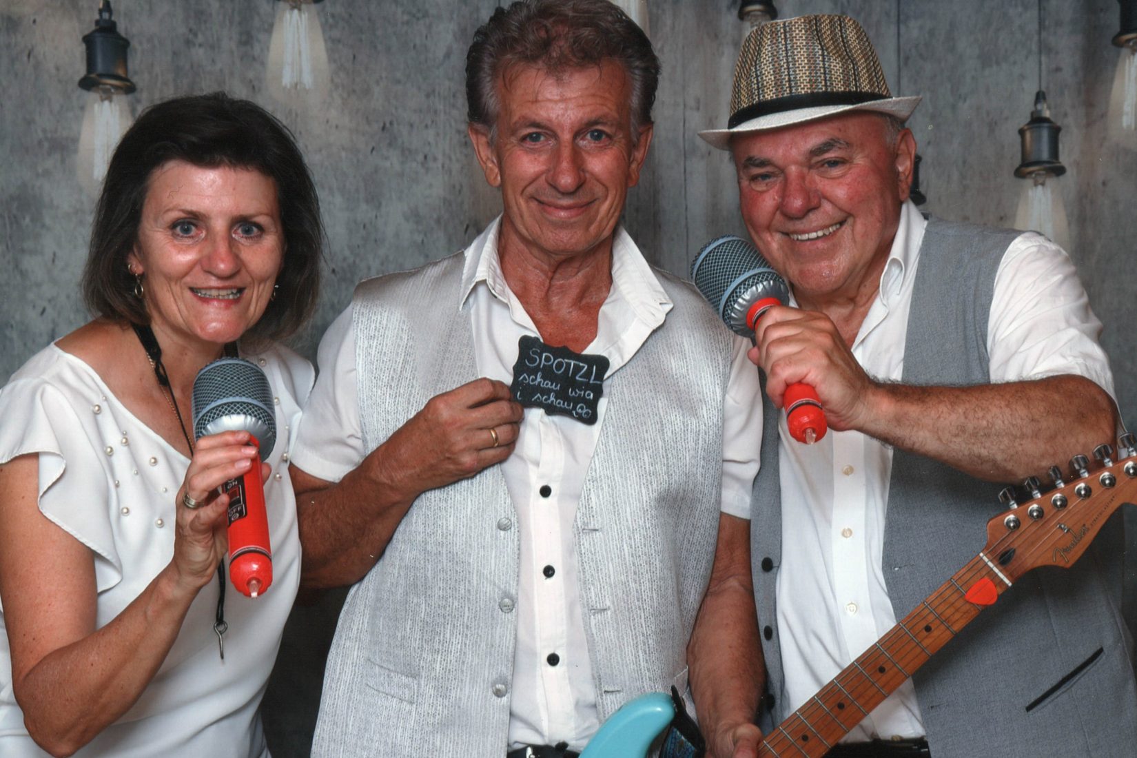Das LETTERS TRIO in weißen Outfits mit Mikrofonen und Gitarre